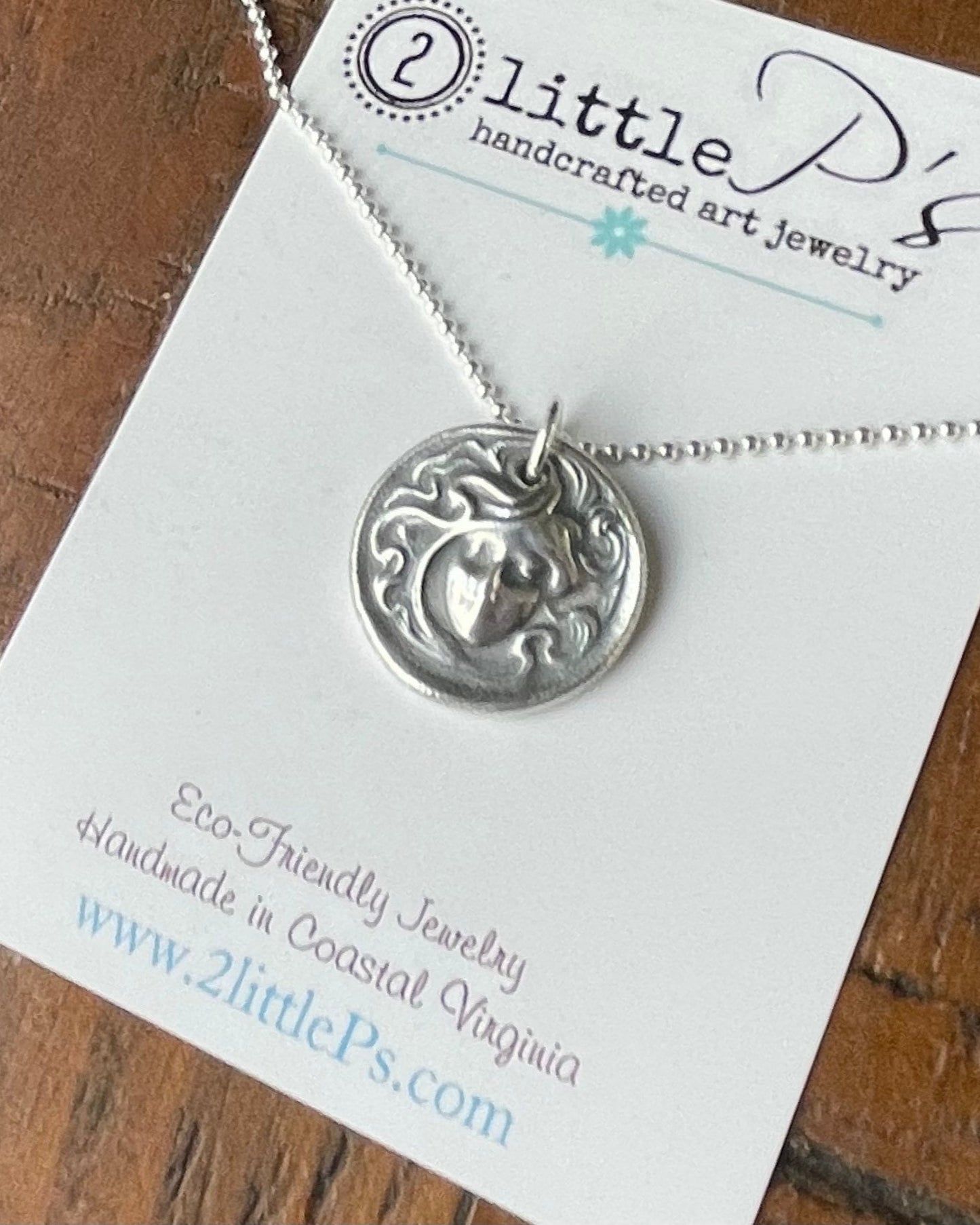 A handcrafted silver mermaid lady pendant necklace presented on a card with the 2 little P's brand and website.