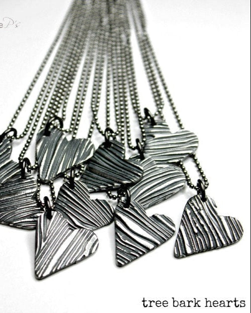 A collection of heart-shaped necklaces with a tree bark texture, displayed on a white background.
