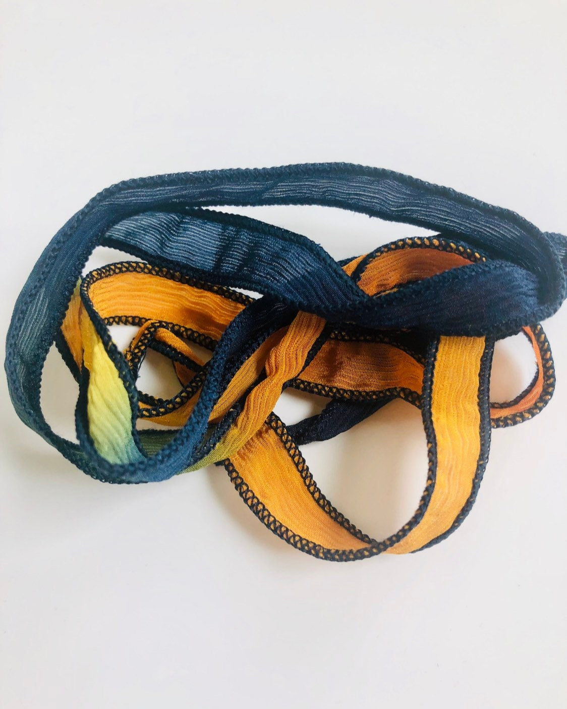 A navy and light orange silk wrap ribbon, approximately 36 inches long, sewn to a point.