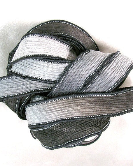A coiled silk wrap ribbon in Jet Black and Charcoal Grey colors, with a textured appearance and sewn edges.