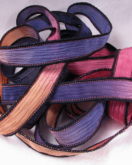 A collection of silk wrap ribbons in hues of purple, navy, orange, and pink, each with a pointed end and sewn together.