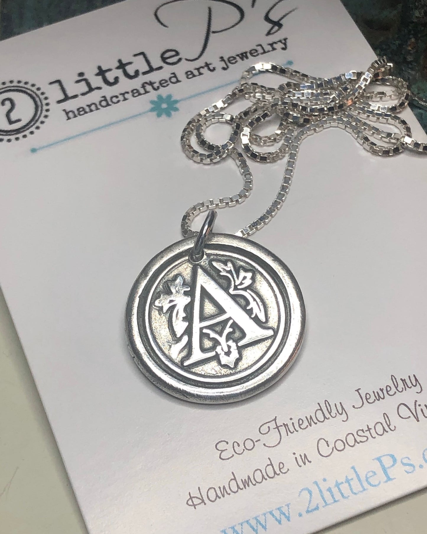 A silver monogram letter A charm necklace displayed on a card with the brand '2 little P's' and the website 'www.2littleps.