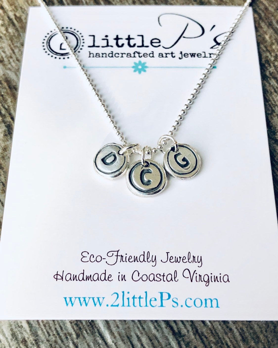 A personalized jewelry necklace with three silver typewriter key charms attached to a sterling silver bead ball chain, presented on a card that reads 'littleP's handcrafted art jewelry', indicating the product is eco-friendly and handmade in coastal Virginia.