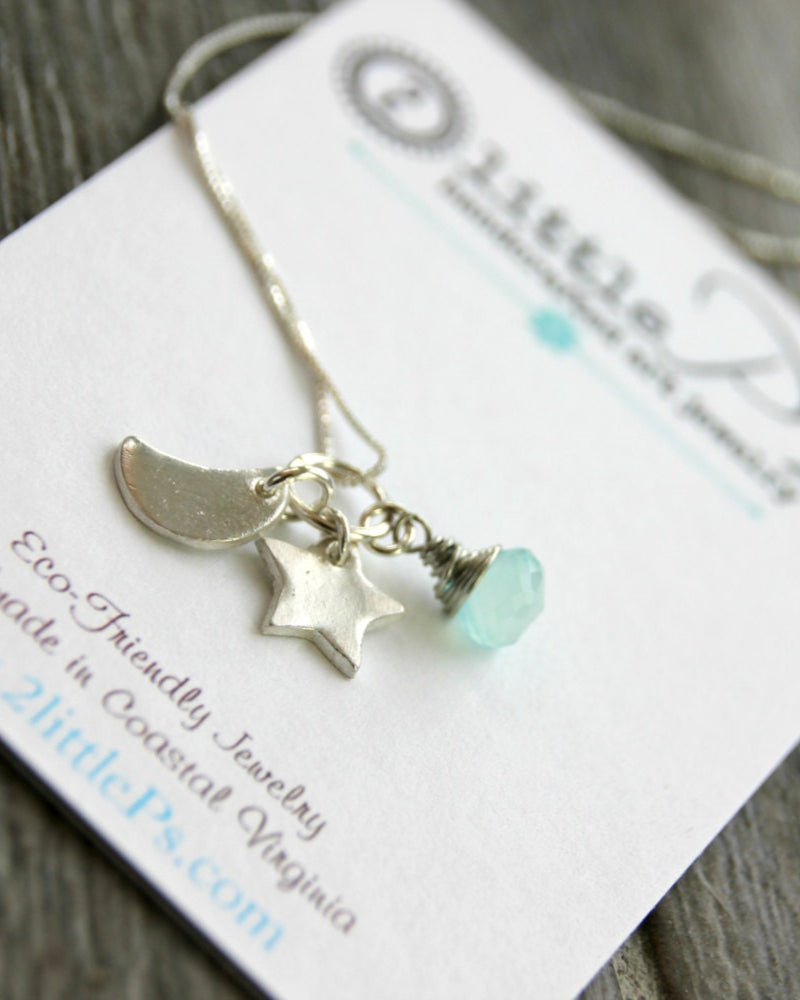 A sterling silver necklace with a silver crescent moon, star, and aqua gem charm, presented on a card with the brand name 'Lantern & Co'.