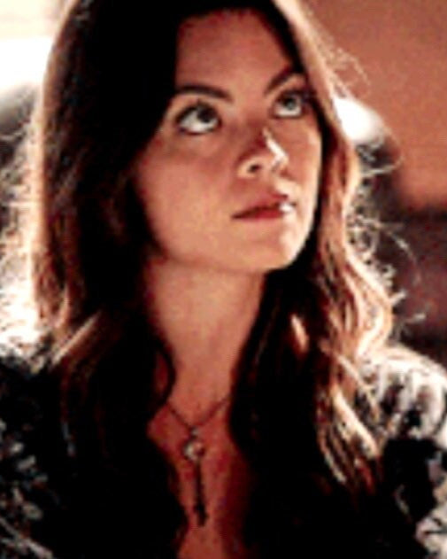 A woman looking off to the side, wearing a necklace with a clear crystal heart pendant.